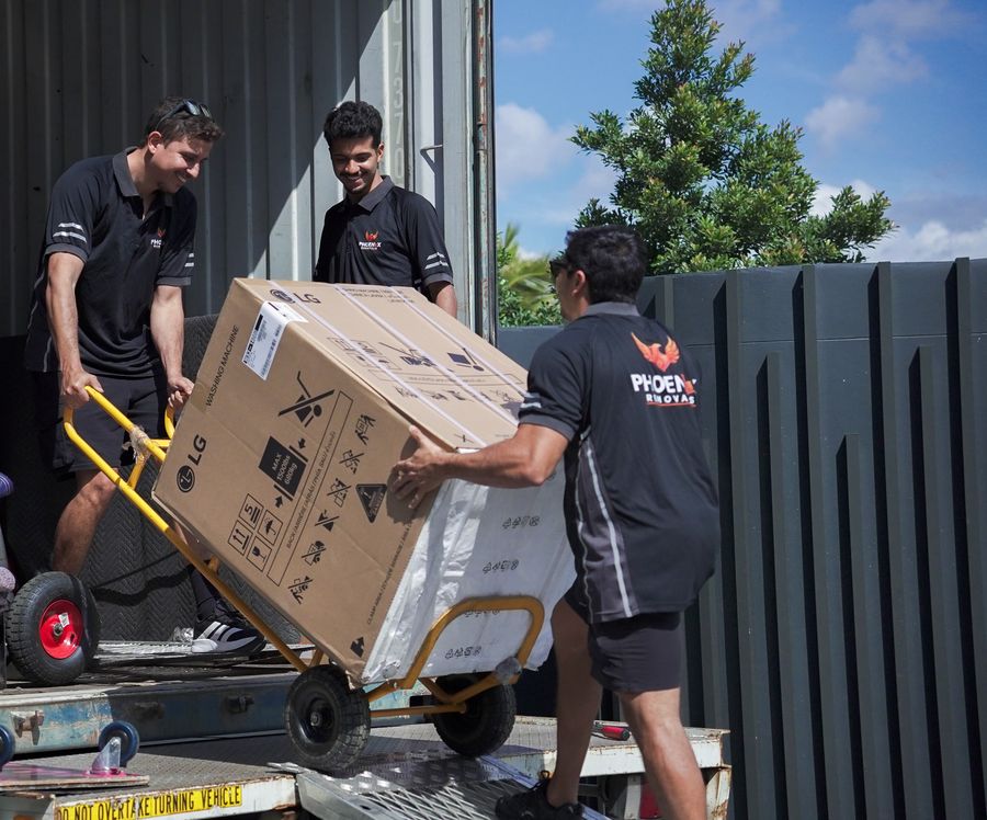 Crew loading a packed box up the truck ramp on a trolley